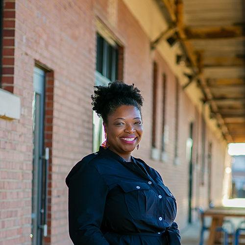 Kimberly Geter Smiling African American female standing outside of a brick building.